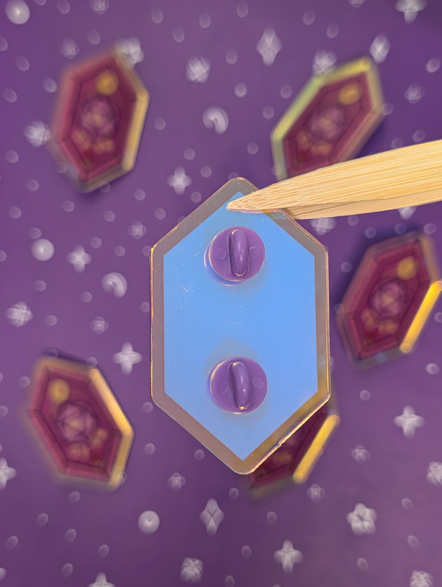 Hexagonal pin back with purple rubber backs on a purple background with star patterns