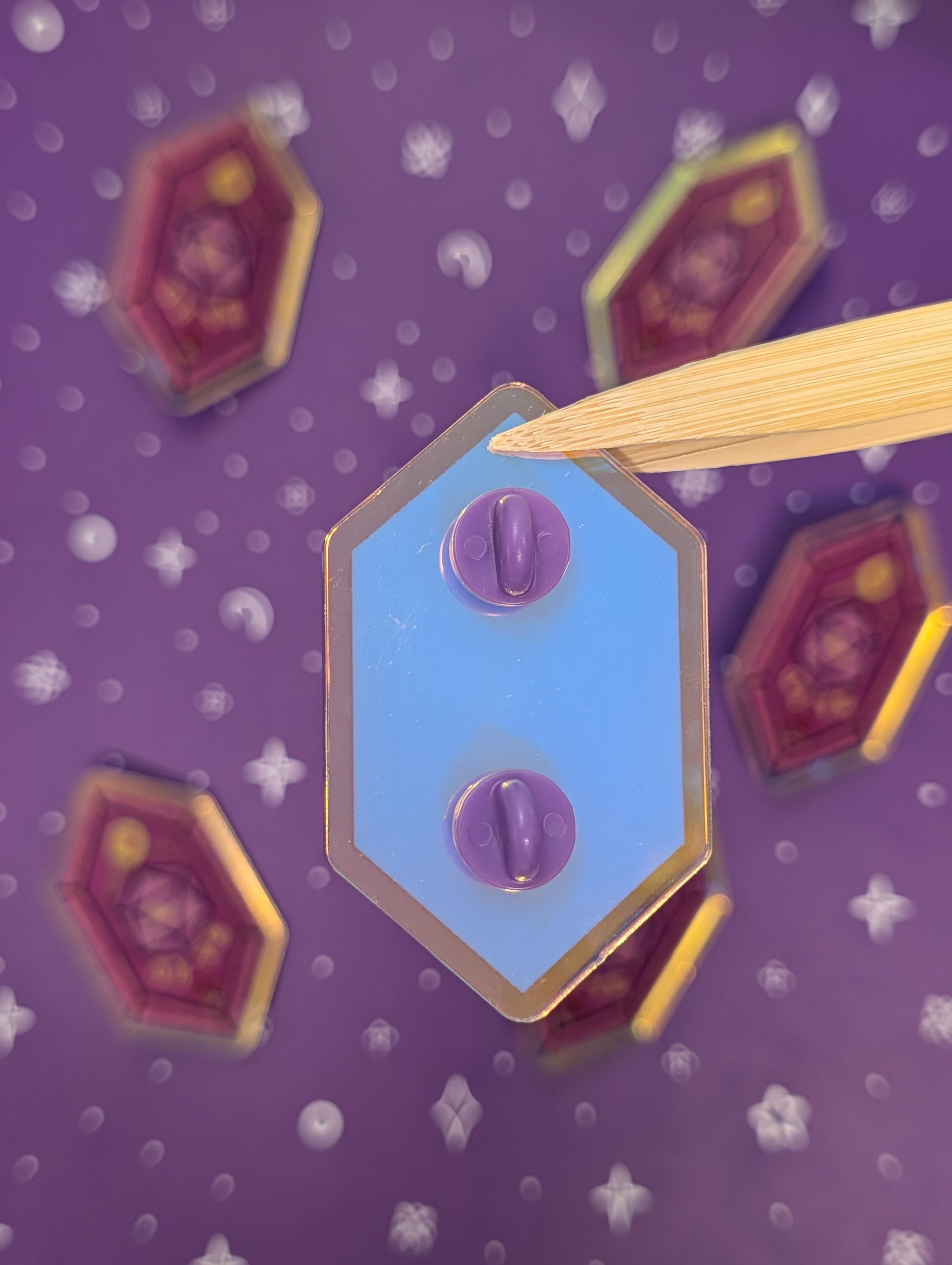 Hexagonal pin back with purple rubber backs on a purple background with star patterns