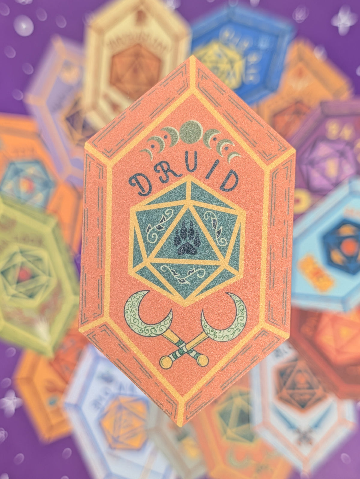 A stylized illustration of a d20 die rolling with a paw print symbol and the word 'DRUID' on an orange hexagonal sticker, surrounded by colorful blurred polyhedral dice on a purple background.